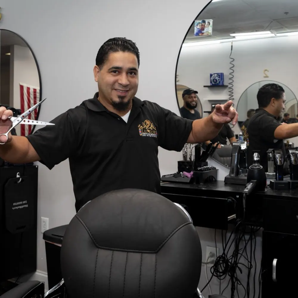 Barber smiling at his station with scissors in hand