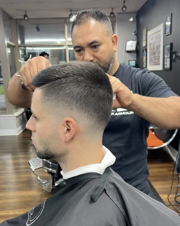 Barber shaping a client's fade in the chair